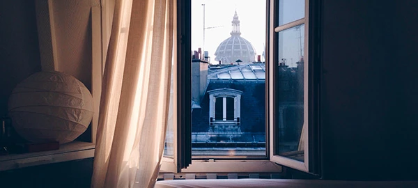 fenêtre ouverte avec vue sur les toits de Paris