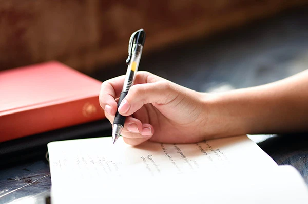 main tenant un stylo et écrivant dans un cahier